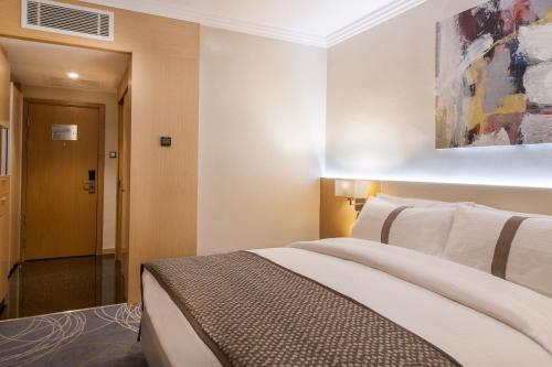 a bedroom with a bed and a painting on the wall at Mövenpick Hotel Amman in Amman