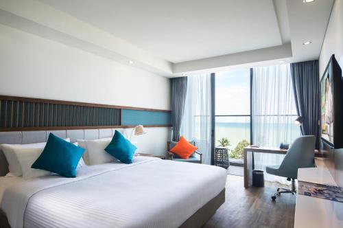 Habitación de hotel con cama con almohadas azules y naranjas en Citadines Bayfront Nha Trang en Nha Trang