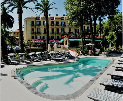 une piscine avec des chaises et un hôtel en arrière-plan dans l'établissement Hotel Metropole, à Santa Margherita Ligure