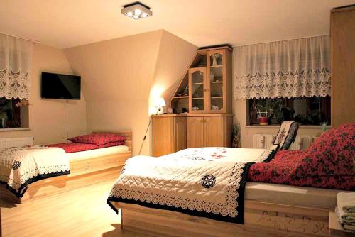 a bedroom with two beds and a tv in it at Willa Gorska Koleba in Zakopane