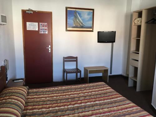 a bedroom with a bed and a chair and a tv at Hôtel Belle Vue d'Angleterre in Le Grau-du-Roi