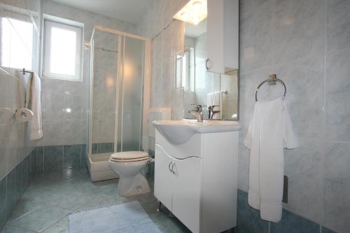 een badkamer met een wastafel, een toilet en een douche bij Apartments Bogović in Malinska