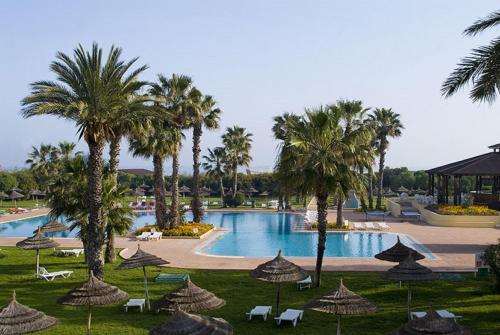 a resort with a pool with palm trees and umbrellas at Sahara Beach Aquapark Resort in Monastir