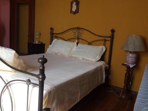 a bedroom with a bed with white sheets and a lamp at Villa Rina in Camo