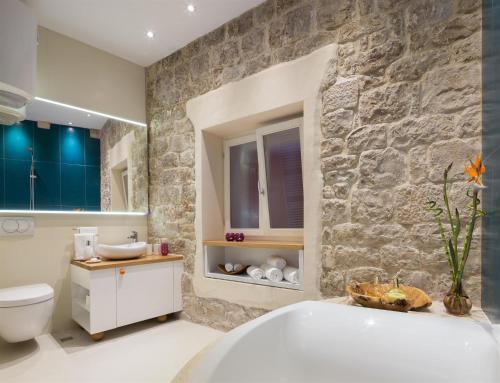 a bathroom with a white tub and a stone wall at That place studio apartment in Trogir