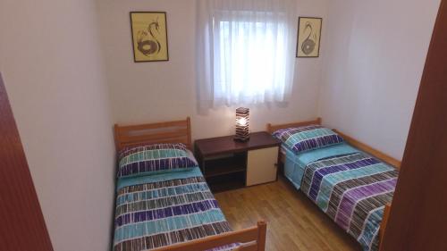 a room with two beds and a desk and a window at Apartment Branko Brodarica in Brodarica