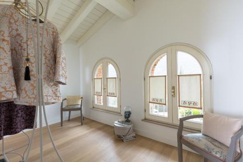 a room with two arched windows and a chair at Villa dei Colori in Toscolano Maderno