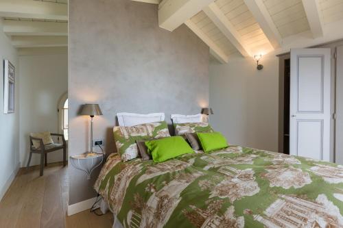 a bedroom with a large bed with green pillows at Villa dei Colori in Toscolano Maderno