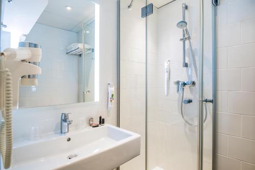 La salle de bains est pourvue d'un lavabo et d'une douche. dans l'établissement ibis Styles Paris 15 Lecourbe, à Paris