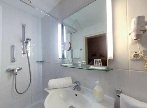 a white bathroom with a sink and a mirror at Regina in Heidelberg