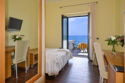 a room with a bed and a table and a balcony at Villa Nettuno in San Menaio