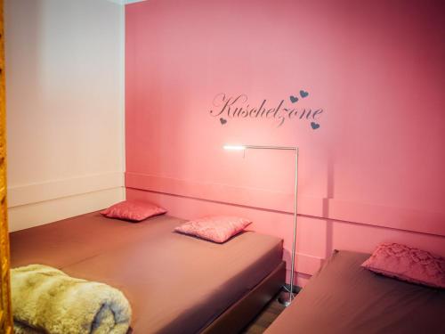 two beds in a room with pink walls at Hotel Antoniushof in Ruhstorf