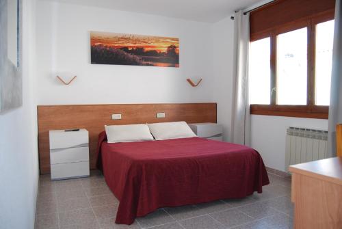 a bedroom with a bed with a red blanket at Hotel Paradís in Torredembarra