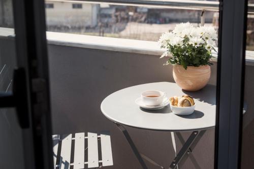 a table with a cup of coffee and a vase of flowers at White Luxury in Thessaloniki