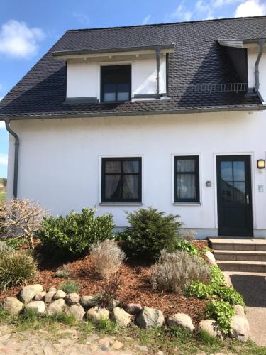 a white house with a black roof at Ferienwohnung auf Rügen mit Boddenblick in Groß Zicker