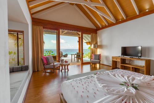 a bedroom with a bed and a view of the ocean at Kudafushi Resort & Spa in Raa Atoll