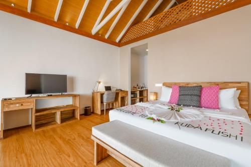 a bedroom with a large bed and a tv at Kudafushi Resort & Spa in Raa Atoll