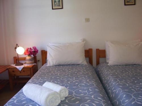 a bedroom with two beds and a table with a lamp at Ioli Apartments in Naousa
