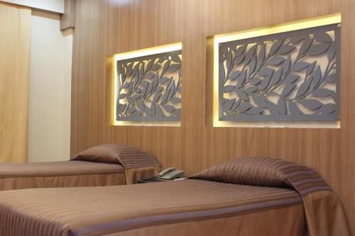 two beds in a room with wooden walls at Charoen Hotel in Udon Thani