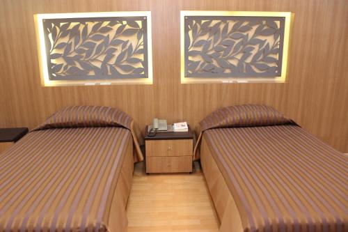 two beds in a room with wooden walls at Charoen Hotel in Udon Thani