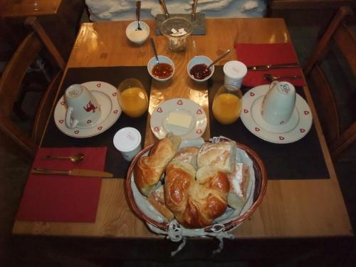 a table with a plate of croissants and cups of orange juice at Le Domaine du Grand Cellier Chambres d'hôtes en Savoie in Tournon