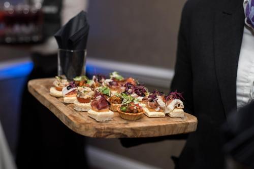 a person holding a tray of food on a cutting board at Mercure Milton Keynes Hotel in Milton Keynes
