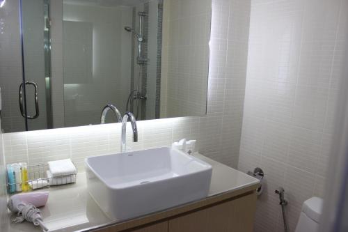 a white bathroom with a sink and a mirror at Charoen Hotel in Udon Thani