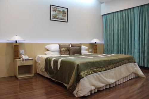 a bedroom with a large bed with a green curtain at Charoen Hotel in Udon Thani