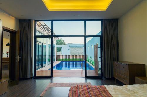 a bedroom with a large glass door with a swimming pool at Villa Blanche in Unayzah