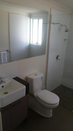 a white bathroom with a toilet and a sink at Dooleys Tavern and Motel Capella in Capella