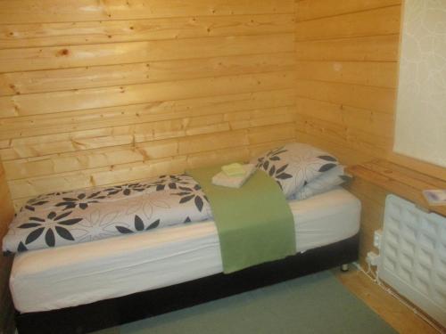 ÞórshöfnにあるSmyrill Cottagesの小さなベッドルーム(木製の壁のベッド付)
