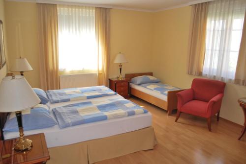 Pokój hotelowy z 2 łóżkami i czerwonym krzesłem w obiekcie Hotel Zachs w mieście Sankt Margarethen im Burgenland