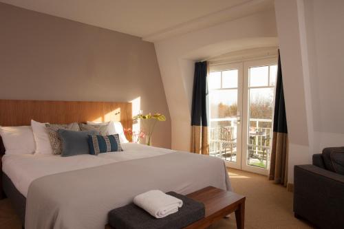 Un dormitorio con una gran cama blanca y una ventana en Grand Hotel Ter Duin en Burgh Haamstede