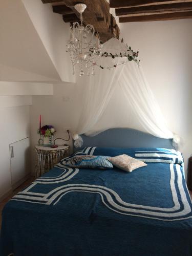 a bedroom with a blue bed with a chandelier at La casina delle rondini in Corsanico-Bargecchia