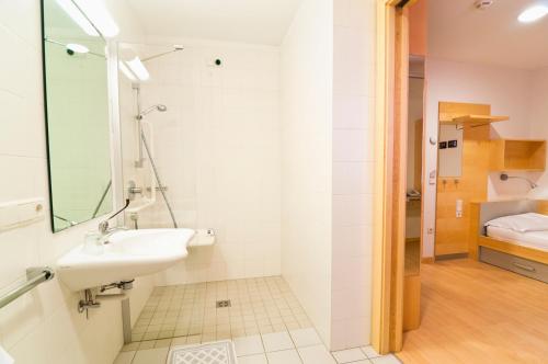 a white bathroom with a sink and a bedroom at Kolpinghaus Bolzano in Bolzano