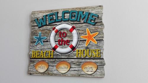 a welcome to the beach house sign with a life preserver at Guest House Pereira in Vila Praia de Âncora