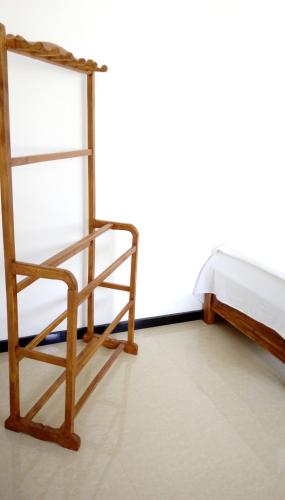 a wooden shelf and a chair next to a bed at Dreams Villa in Hikkaduwa