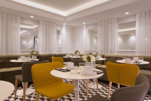 a dining room with tables and yellow chairs at Hôtel Pastel Paris in Paris