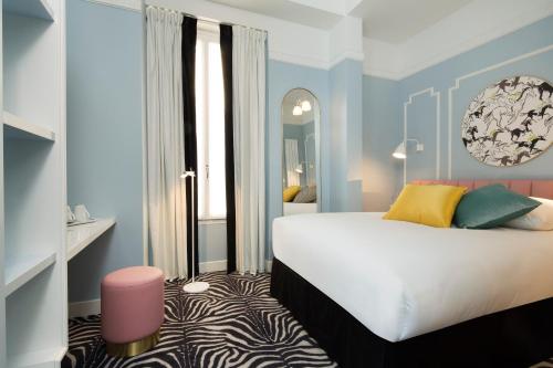a bedroom with a large bed and a mirror at Hôtel Pastel Paris in Paris