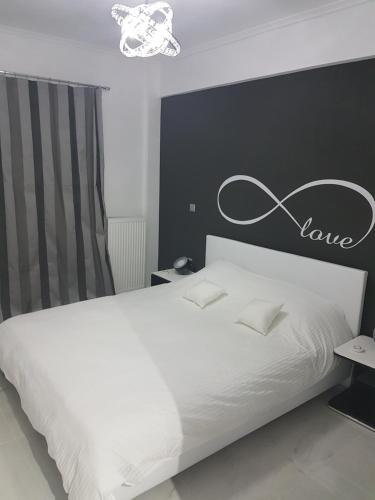 a bedroom with a white bed with a love sign on the wall at Route 77 in Thessaloniki
