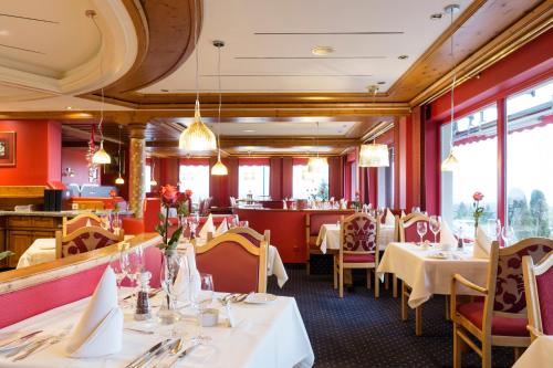 a restaurant with white tables and chairs and windows at Wellness-& Nationapark Hotel Schliffkopf, BWSC in Baiersbronn