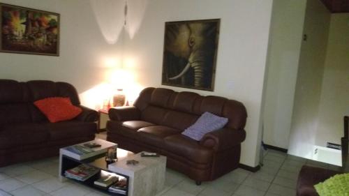 a living room with a brown couch and a table at Hospedaria Ondas do Rosa in Praia do Rosa
