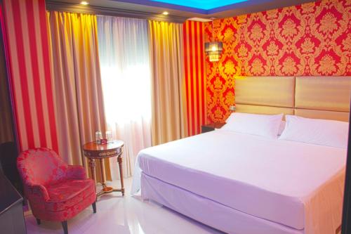 a bedroom with a bed and a red chair at Hotel Años 50 in Torremolinos