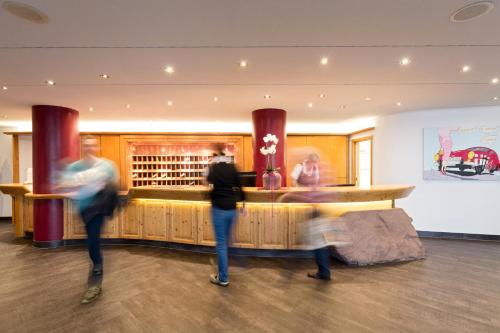 two people standing in front of a bar at Wellness-& Nationapark Hotel Schliffkopf, BWSC in Baiersbronn