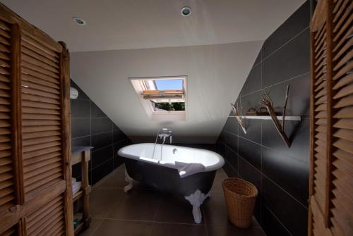 La salle de bains est pourvue d'une baignoire en noir et blanc et d'un lavabo. dans l'établissement Hotel Du Grand Cerf & Spa, à Lyons-la-Forêt