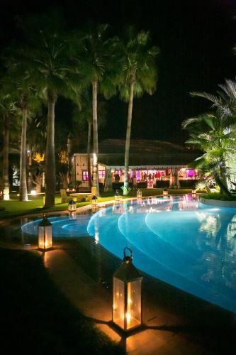a swimming pool with lights and palm trees at night at Lodge K in Marrakech