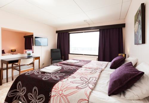 a hotel room with a bed and a desk at Hotel Julie in Joensuu