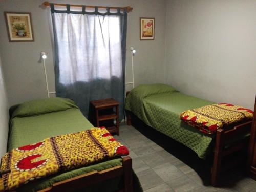 a bedroom with two green beds and a window at Hostal Namaste in Salta