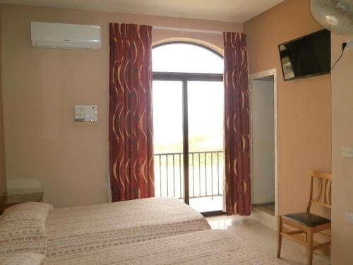 a bedroom with a bed and a large window at Sunset Seaview Accommodation in Marsalforn