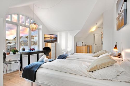 a white bedroom with two beds and a desk at Alfred's Studios in Reykjavík